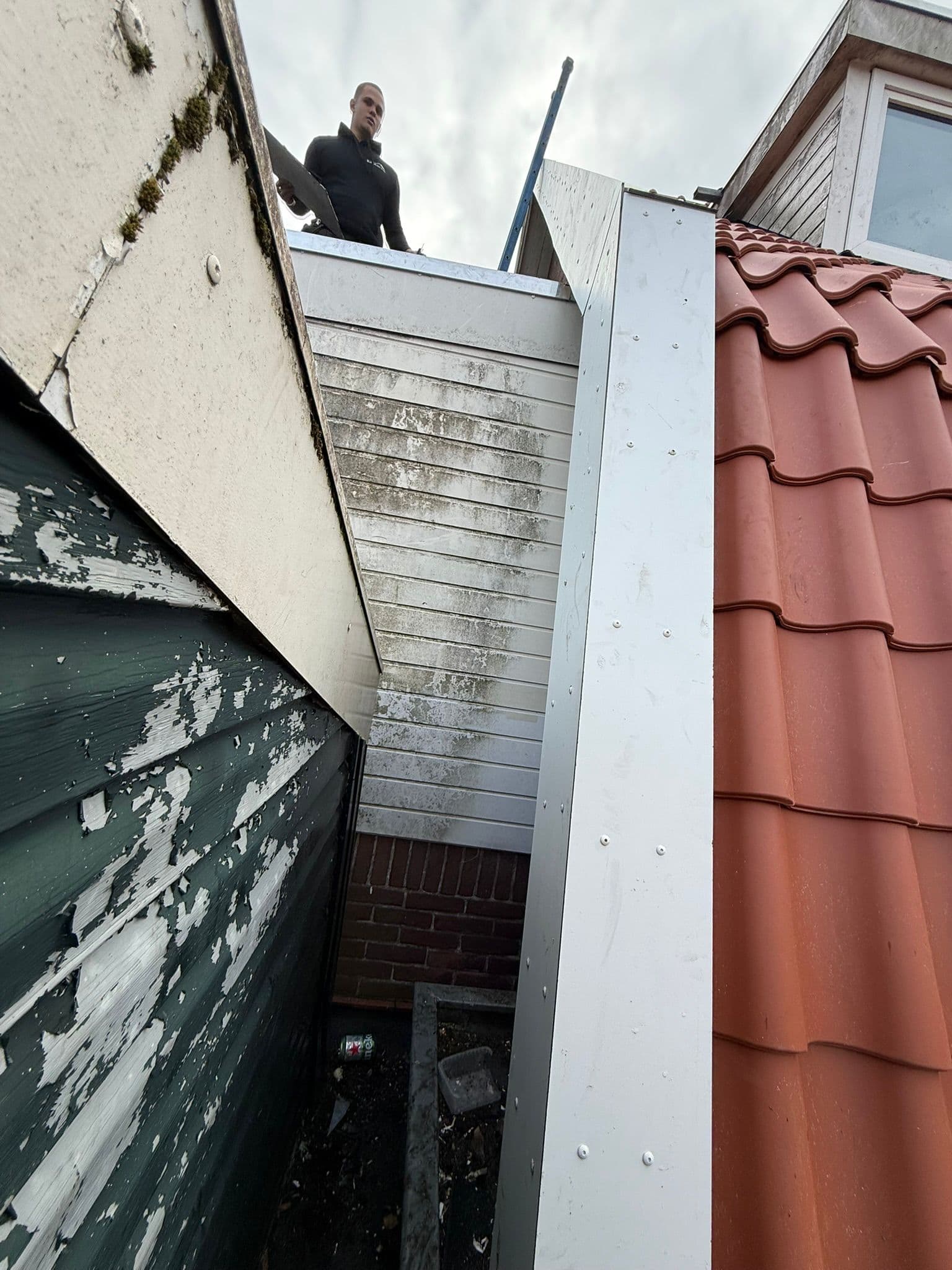 Monteur plaatst nieuw zinkwerk op het boeideel tussen twee woningen