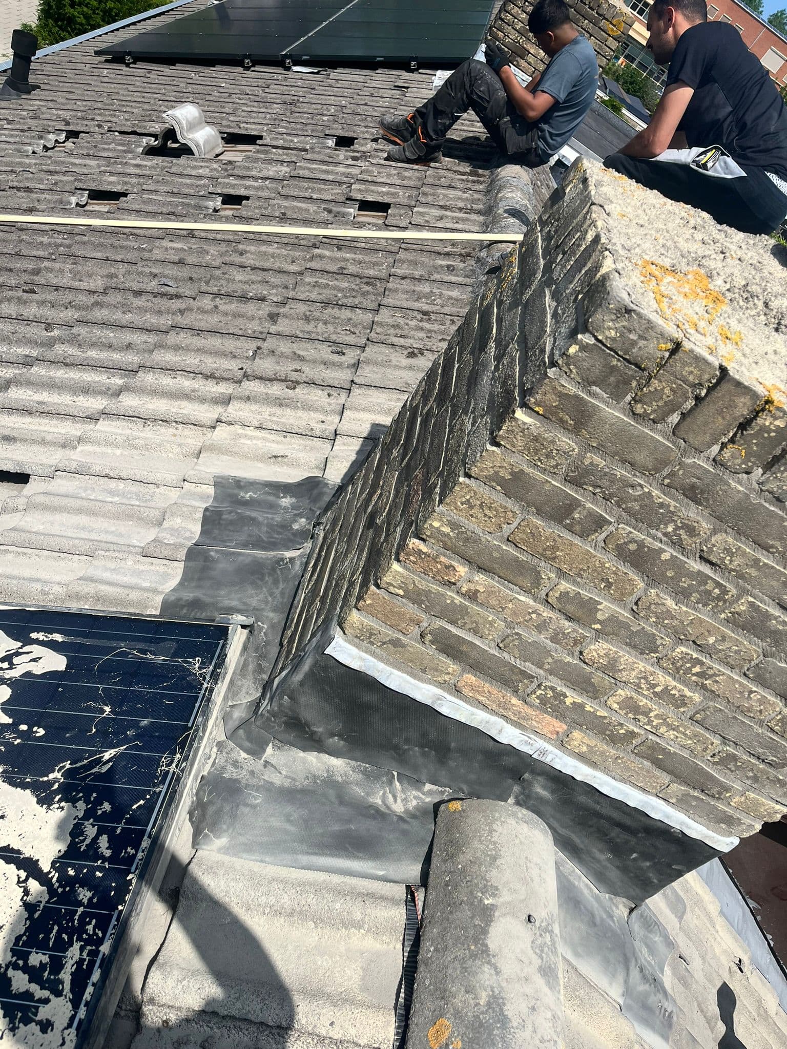 Dakdekkers van BuildCore Techniek aan het werk bij een schoorsteen op een pannendak