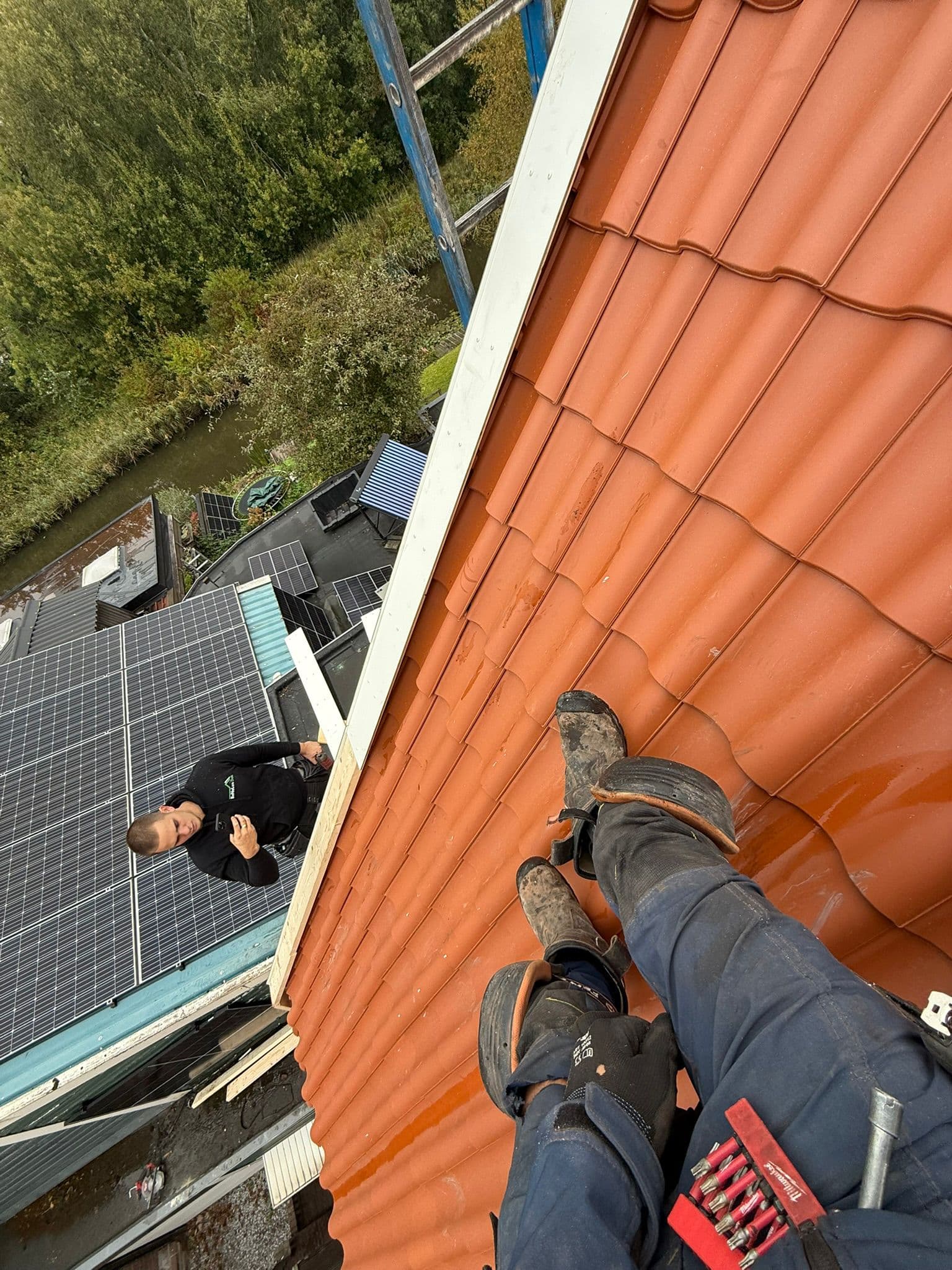 Dakdekkers van BuildCore Techniek aan het werk op een pannendak naast zonnepanelen